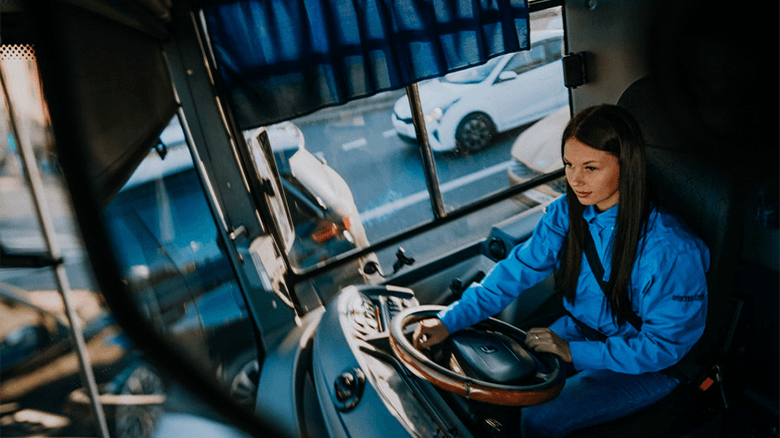 Девушка водитель автобуса в зеркале заднего вида