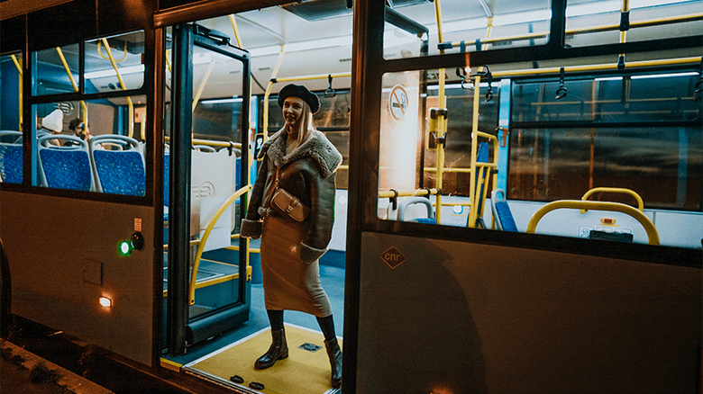 Девушка в берете и кожаной куртке в дверях автобуса