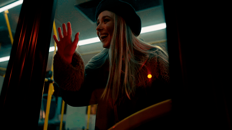 Девушка в берете прислонила руку к стеклянной двери автобуса